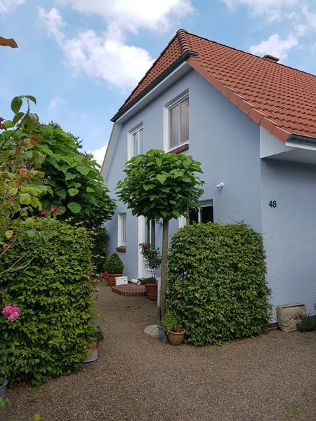 Fassadenanstrich Einfamilienhaus – Malermeister Menken Frisch gestrichenes Einfamilienhaus mit hellblauer Fassade und rotem Ziegeldach