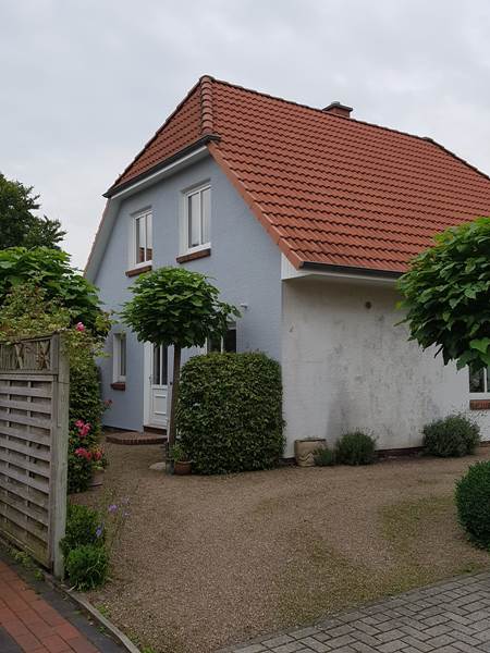 Einfamilienhaus mit verwitterter weißer Fassade vor dem Außenanstrich – bewölkter Himmel