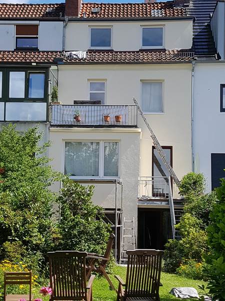 Frisch sanierte cremefarbene Hausfassade eines Reihenhauses nach Putz- und Malerarbeiten